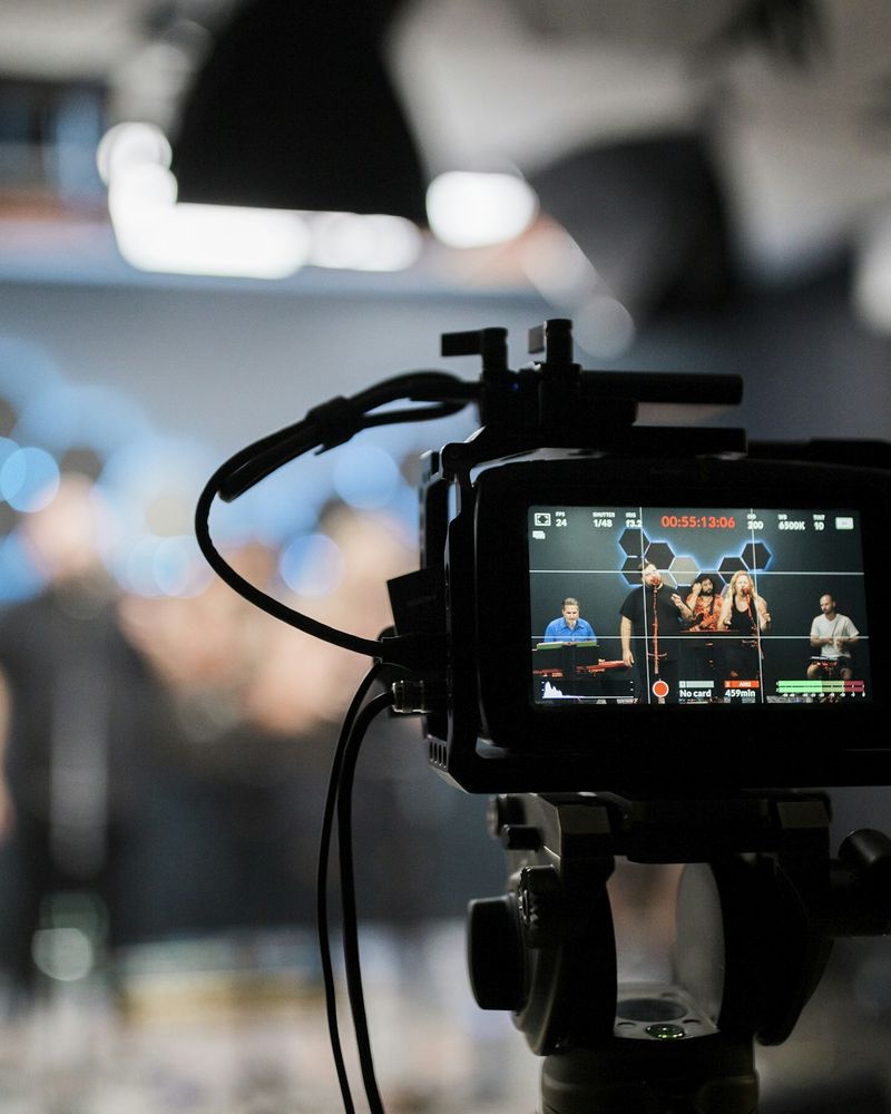 Videokamera mit Monitor filmt eine Band auf der Bühne
