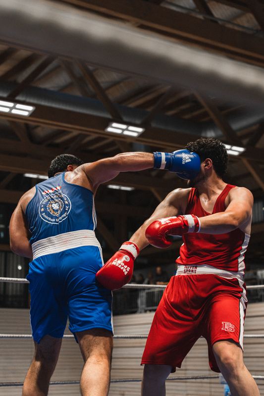 Boxkampf: Der Boxer in Blau trifft seinen Gegner in Rot mit einer Geraden