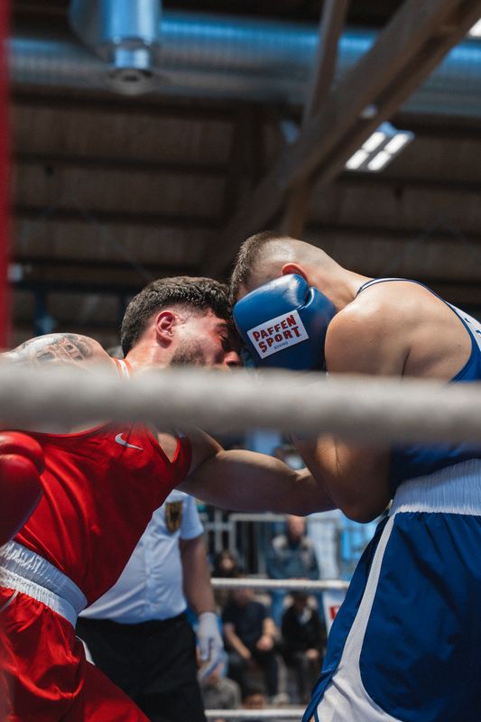 Boxkampf: Zwei Boxer im Clinch, fotografiert durch die Ringseile
