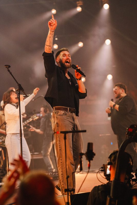 Sänger mit erhobener Faust vor der Band