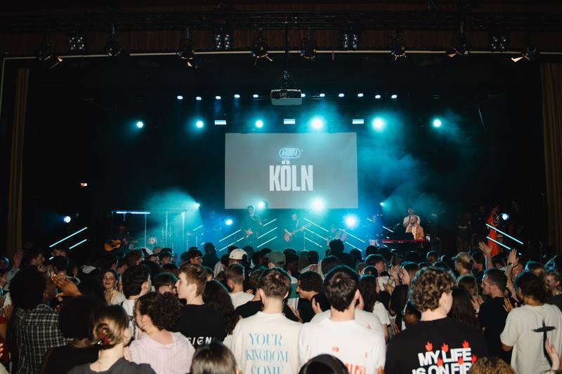 Voller Saal vor beleuchteter Bühne in Köln