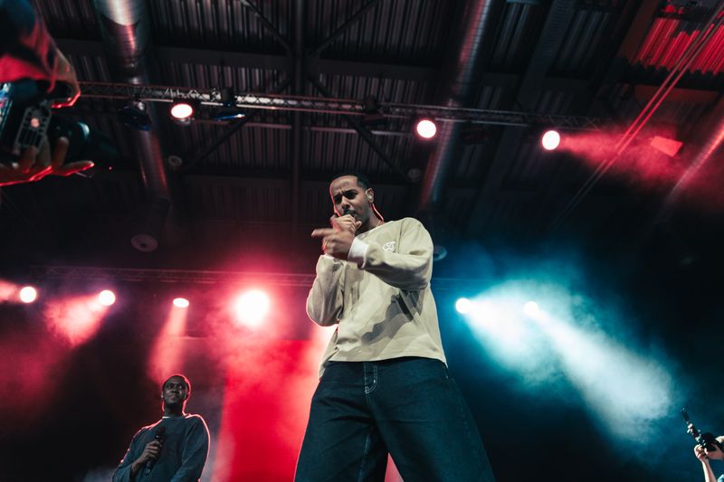 Rapper zeigt in die Kamera, rote und weiße Lichtkegel