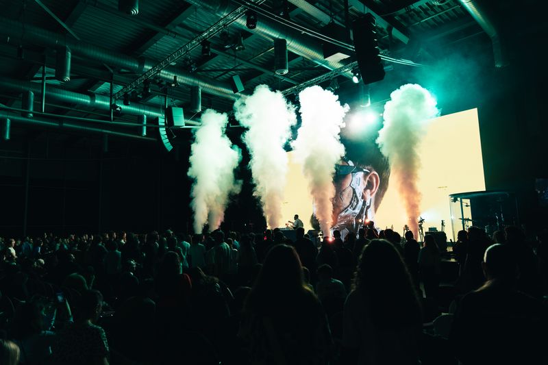 Volle Halle mit bunten CO2-Fontänen über der Bühne